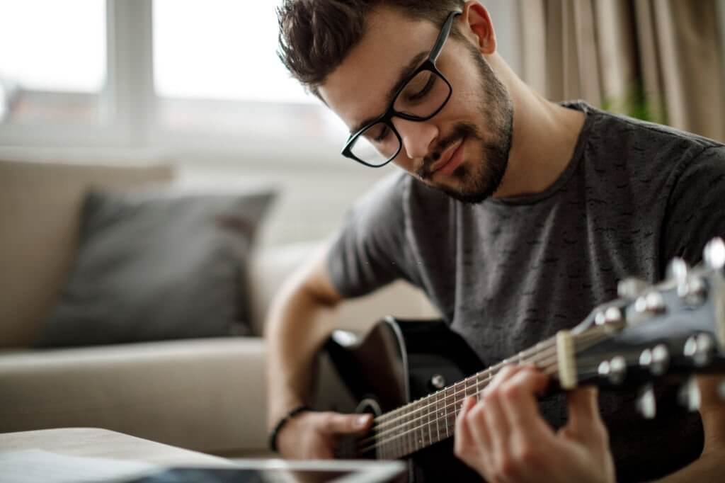 young man playing a guitar at home
